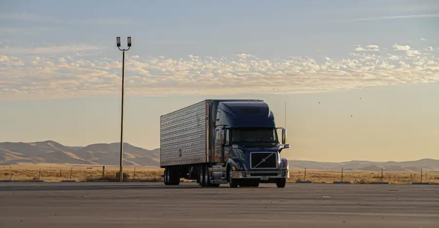 Blue Volvo semi truck parked at sunrise